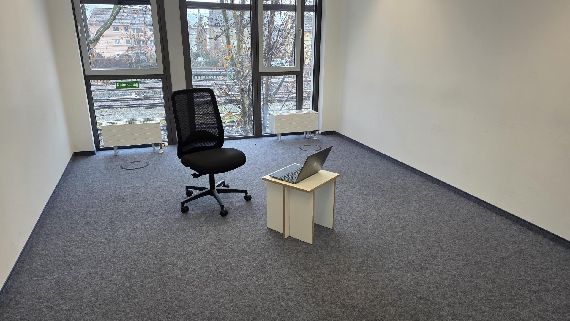 Ein leerer Stuhl in einem leeren Zimmer. Das Fenster geht auf die Deckerstrasse.